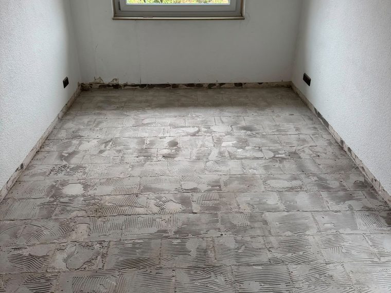 Kleines Zimmer nach dem Rückbau, Bodenfliesen entfernt, Kleberbett liegt frei